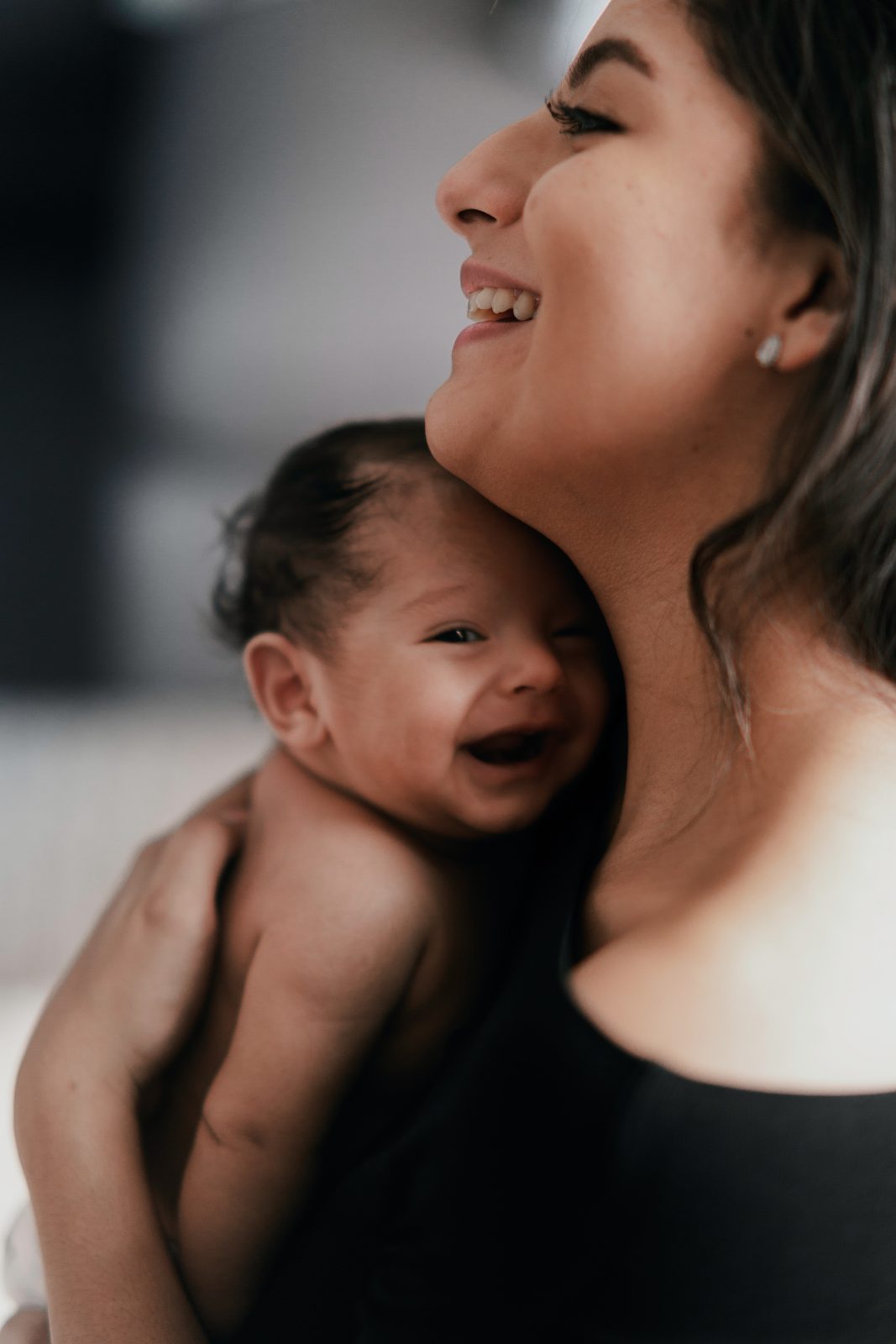 Mother holding her newborn in soft window light